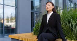 Woman in suit sits outside office breathing fresh air in